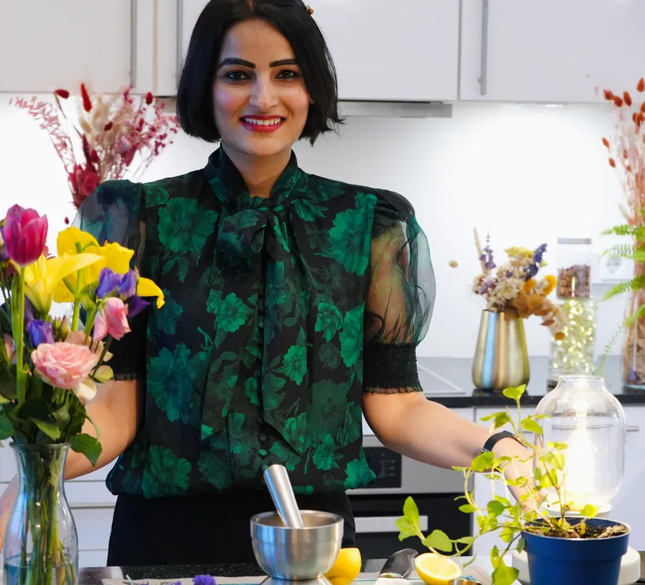 Woman in floral blouse in a kitchen setting.