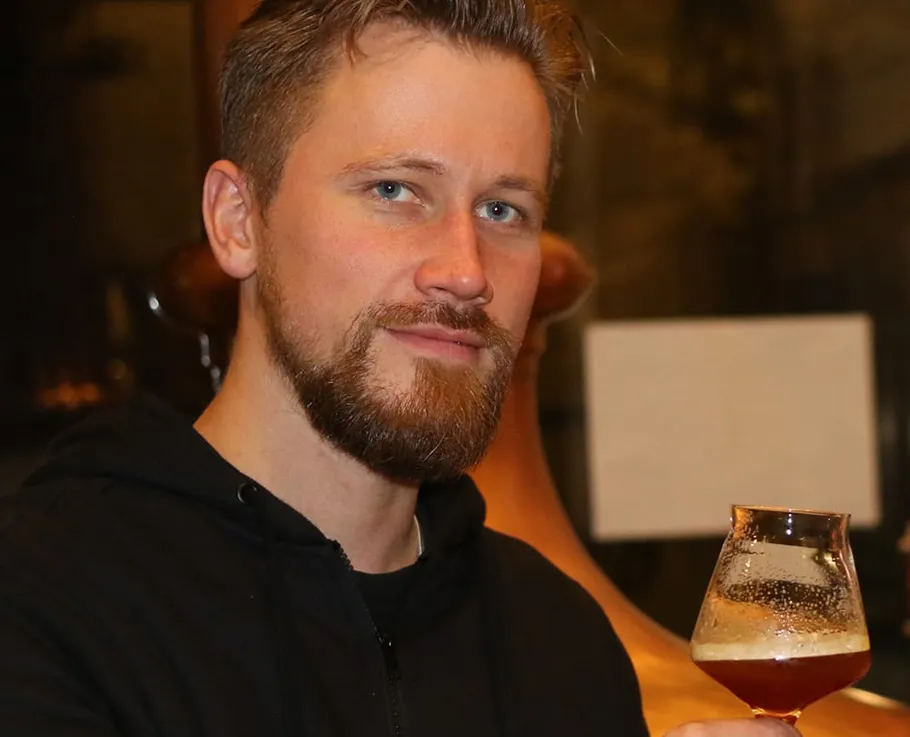 Mann hält ein Bierglas drinnen.