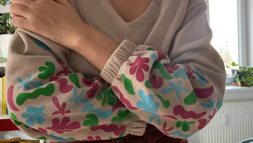 Person wearing sweater with colorful sleeves.