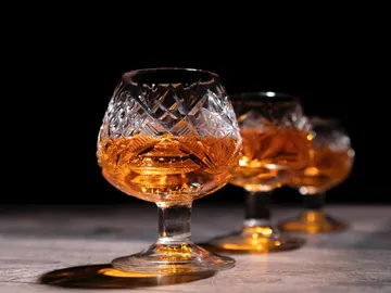 Crystal glasses with orange liquid on a table.
