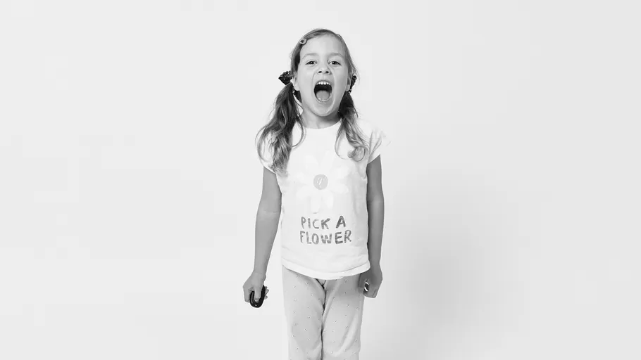 Mädchen schreit, trägt Blumenshirt, weißer Hintergrund.