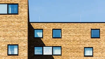 Backsteingebäude mit blauen Fenstern, sonniger Tag.