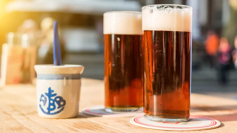 Zwei Biergläser auf einem Holztisch im Freien.
