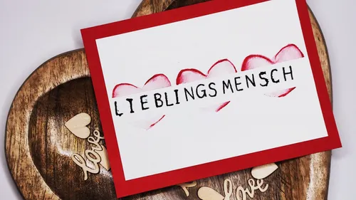 Karte mit Herzen auf Holzuntergrund.