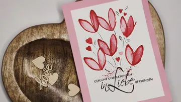 Grußkarte mit roten Blumen auf Holzherz.