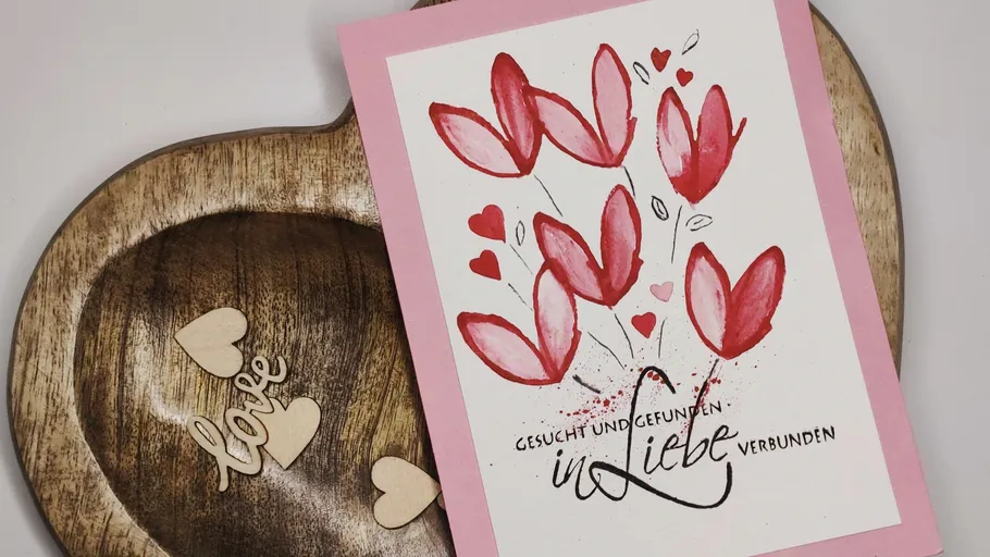 Greeting card with red flowers on wooden heart.