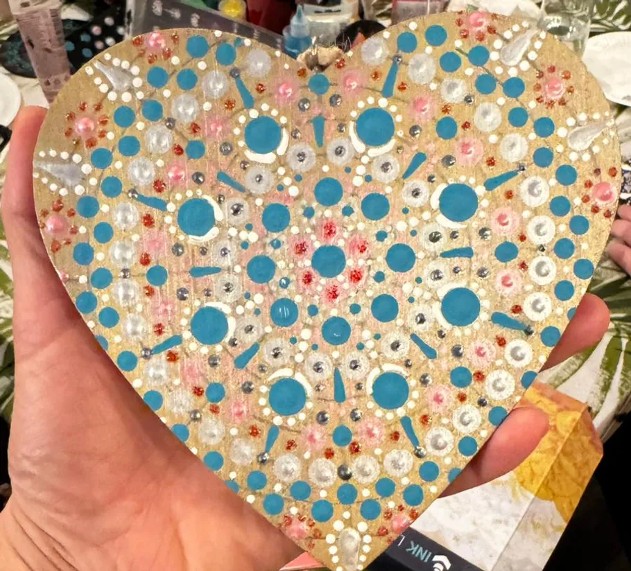 Hand holds decorated wooden heart shape.