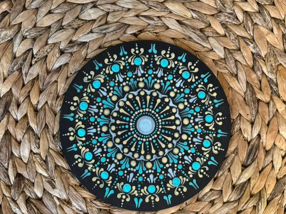 Mandala-Malerei mit blauen Details auf Strohmatte.