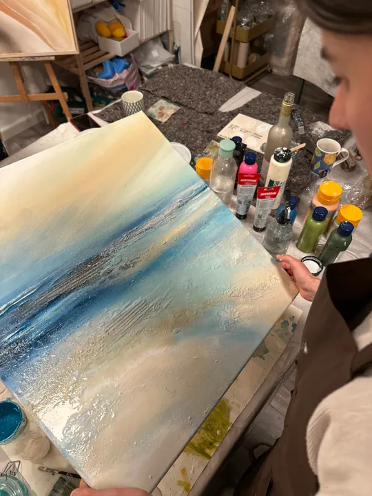 Person hält ozeanisches Gemälde im Kunststudio.