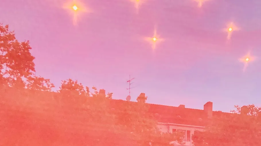 Helle Lichter im rosa Himmel über Gebäude.