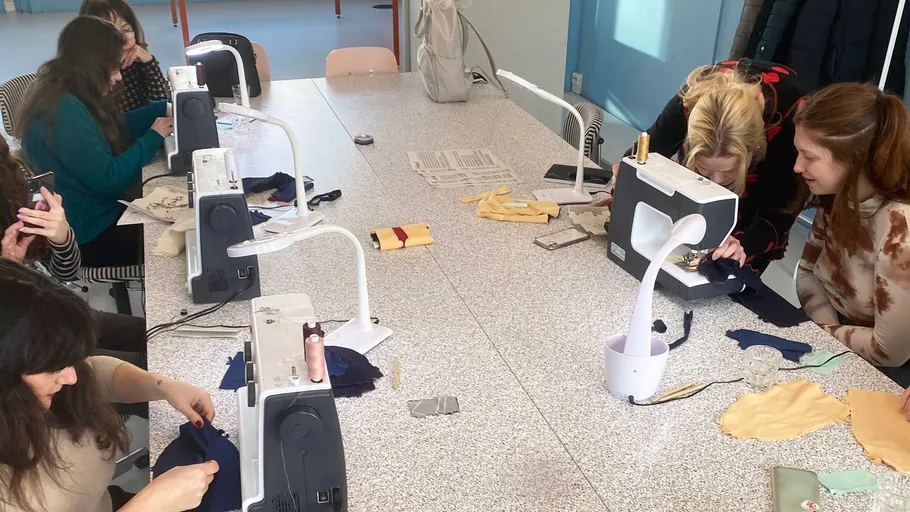 Women sewing with machines in a classroom.