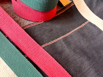 Bunte Stoffriemen auf dunklem Textilhintergrund.