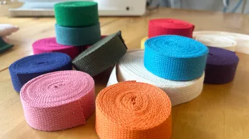 Colorful fabric rolls stacked on table.