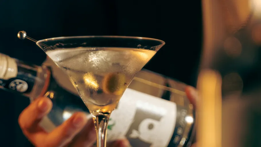 Martini mit Olive im Glas, Flasche daneben.