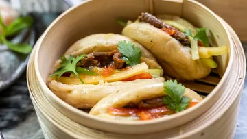 Steamed buns with meat and vegetables in a basket.