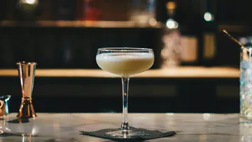 Cocktail glass with drink on bar counter.