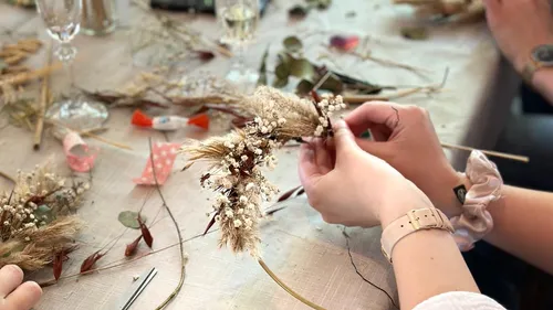 Person bastelt Blumenarrangement auf Tisch.