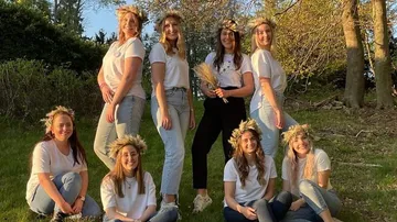 Group of women wearing flower crowns in forest.