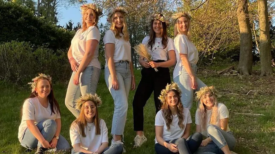 Group of women wearing flower crowns in forest.