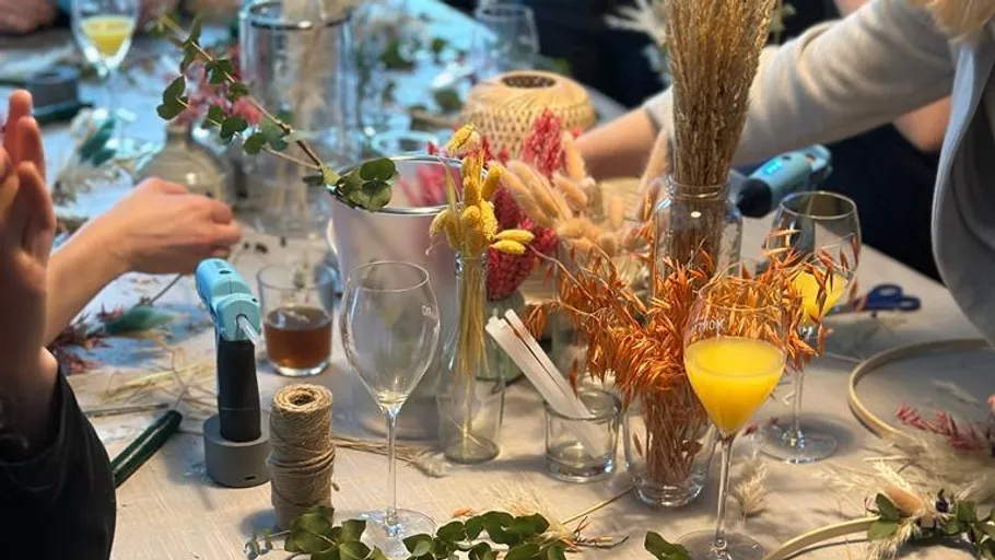 People arranging flowers and leaves on table.