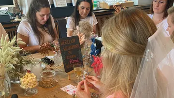 Women crafting floral decorations around a table.