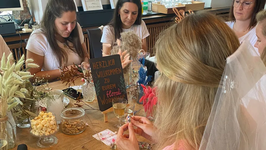 Frauen basteln Blumendekorationen an einem Tisch.
