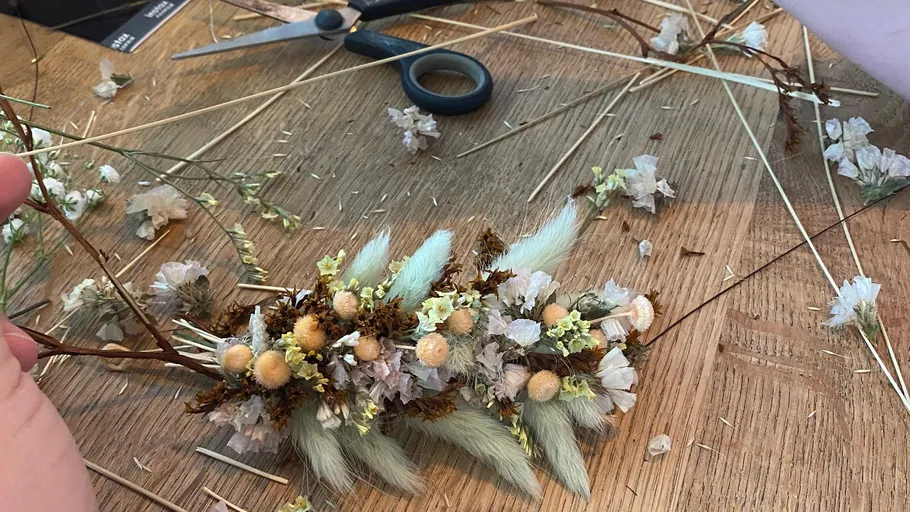 Handcrafting floral wreath with dried flowers.