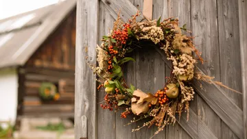 Herbstkranz hängt an Holztür.