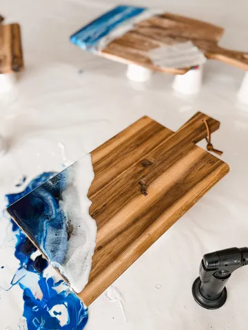 Wooden board with blue resin design on table.