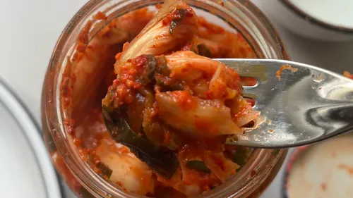 Gabel hält Kimchi über Glas.