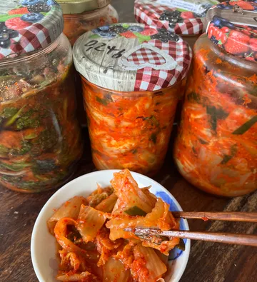 Kimchi jars and bowl with chopsticks on table.