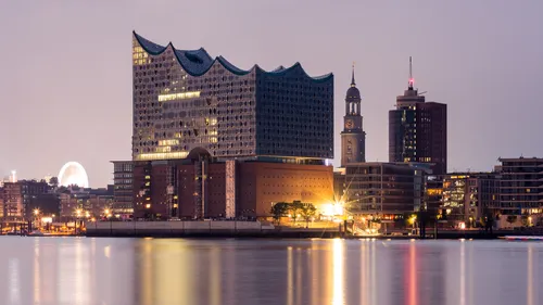 Modern concert hall by the waterfront at dusk.