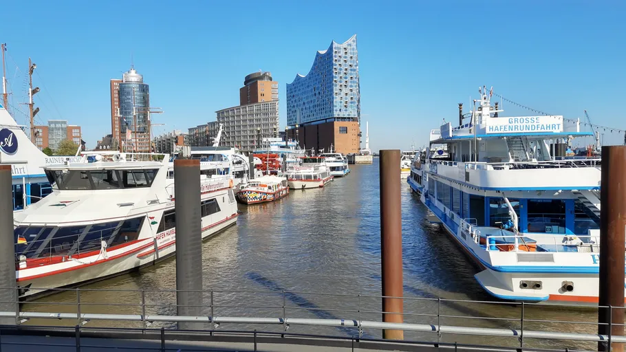 Boats in harbor with modern buildings nearby.