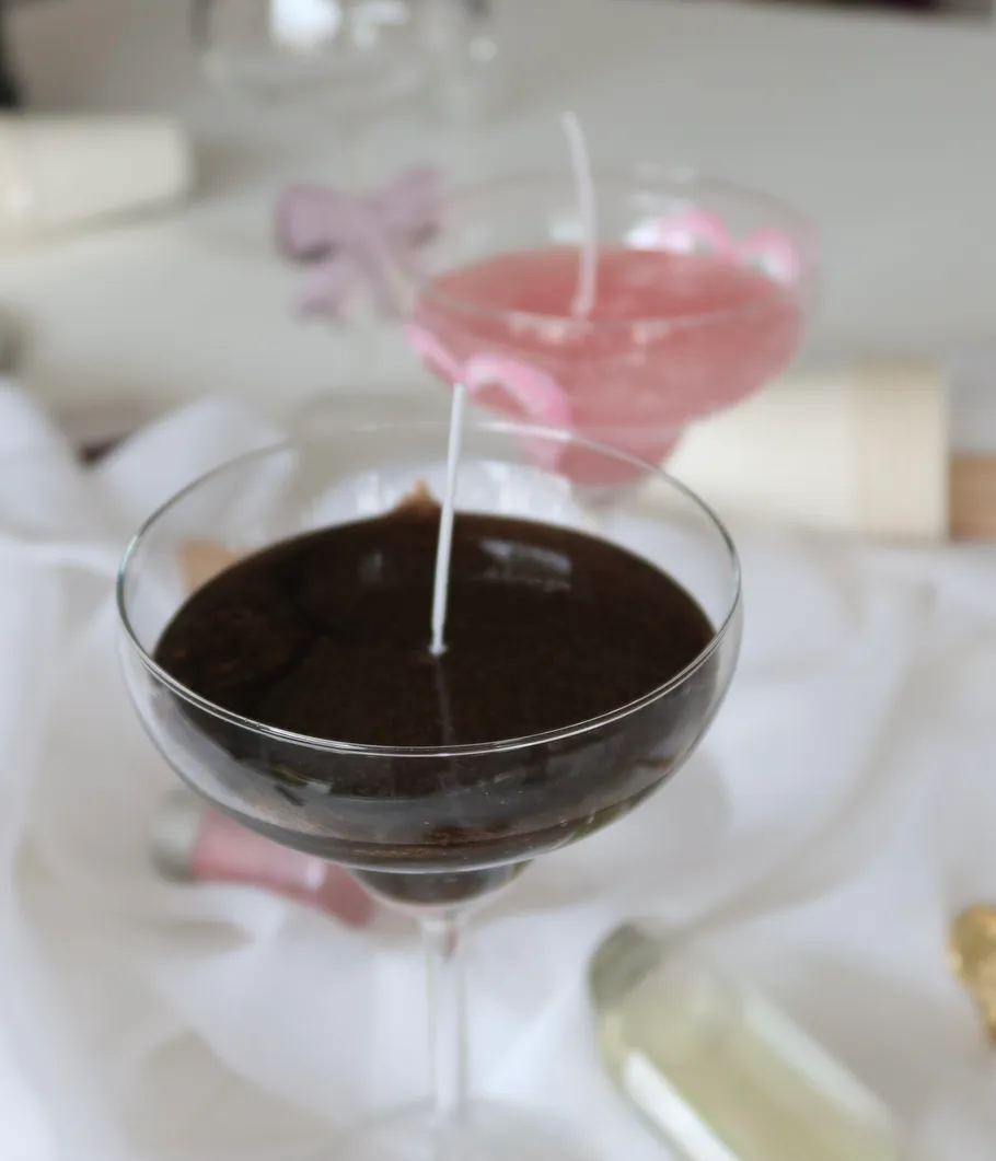 Zwei Kerzen in Gläsern auf Tischdecke.