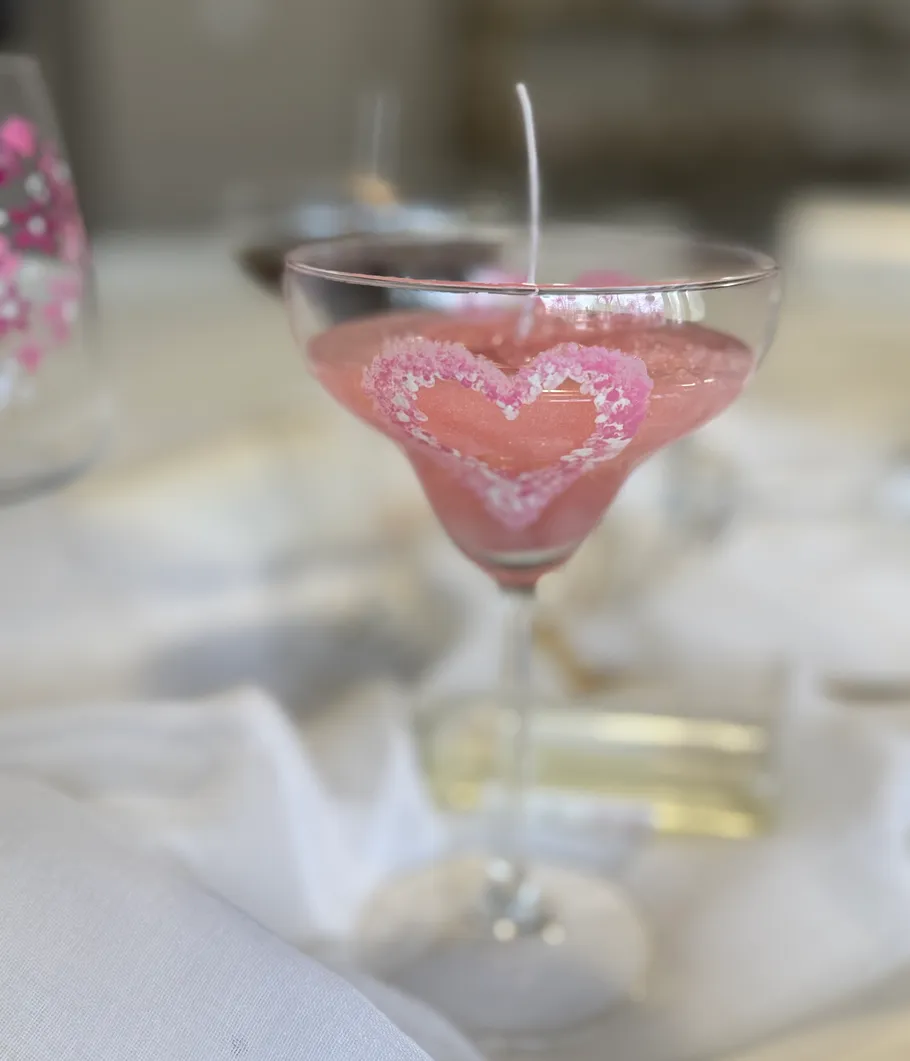 Rosa Kerze im Glas mit Herzmotiv.