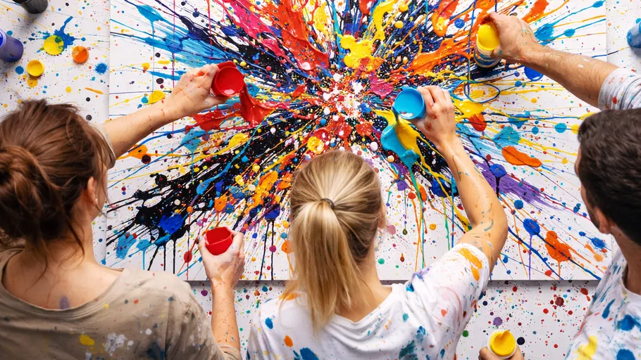 Four people splattering paint on canvas.