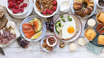 Verschiedene Frühstücksgerichte auf rustikalem Tisch.