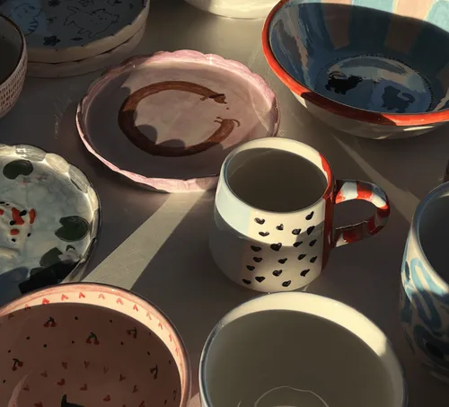 Ceramic dishes and mugs in sunlight.