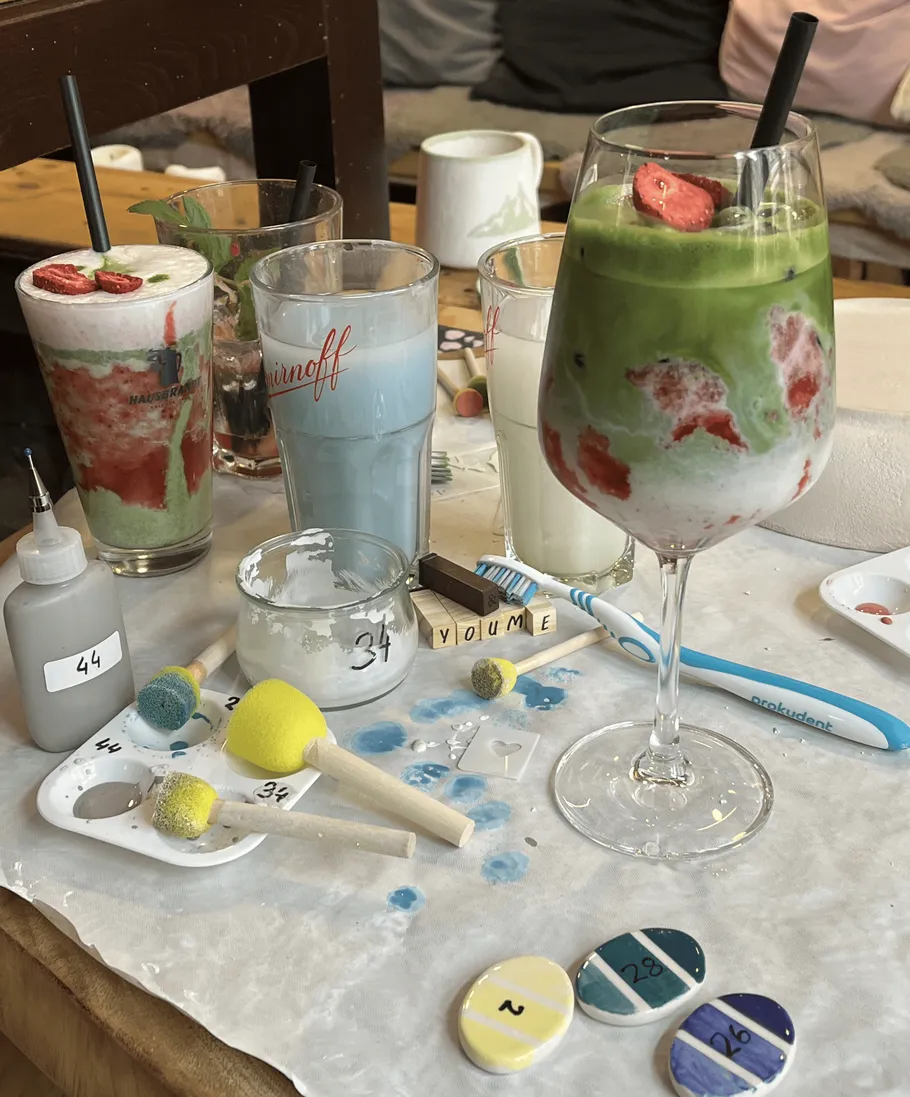 Colorful drinks and painting tools on table.