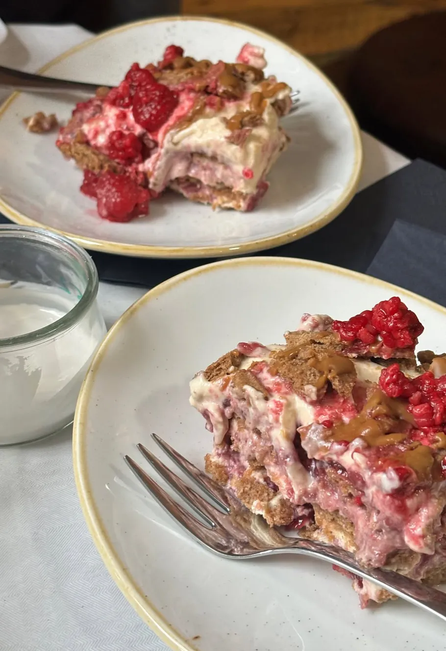 Himbeerdessert mit Sahne und Gabeln auf Tellern.