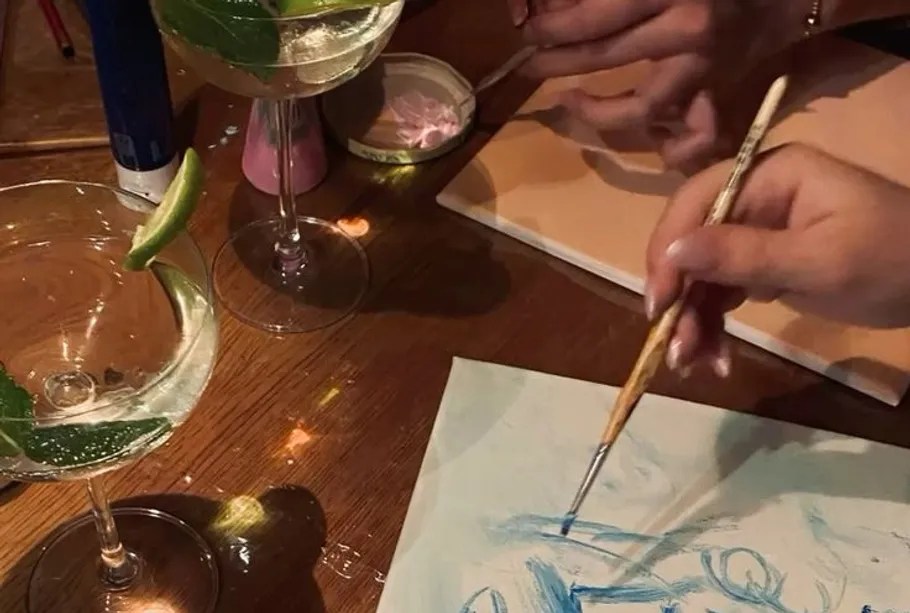 Hands painting with cocktails on table.