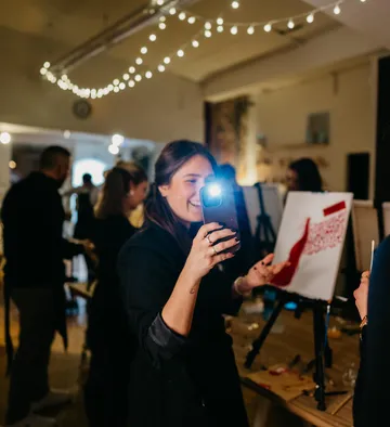 Woman photographing painting in lively art class.