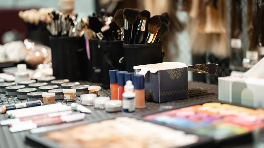 Make-up-Pinsel und Kosmetik auf Tisch.