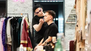 Makeup artist applying cosmetics in dressing room.
