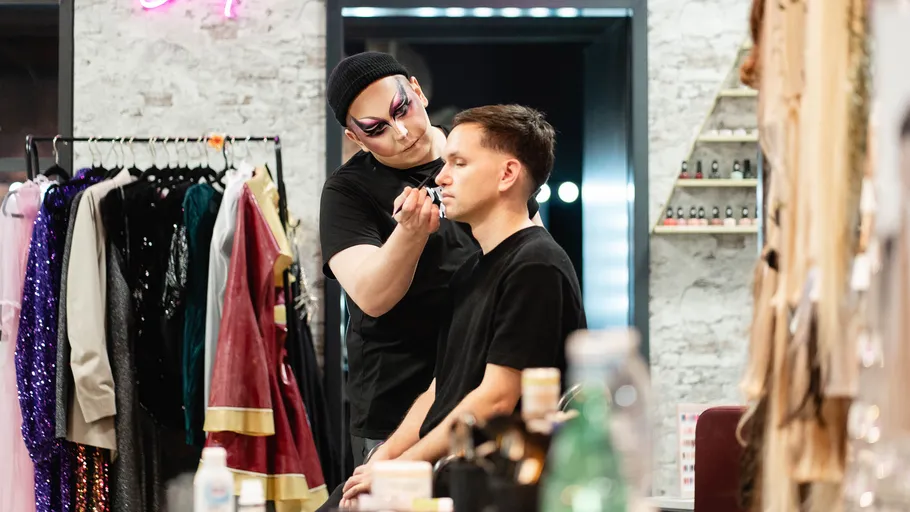 Makeup artist applying cosmetics in dressing room.