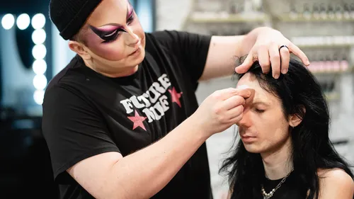 Make-up-Künstler schminkt sitzende Person.