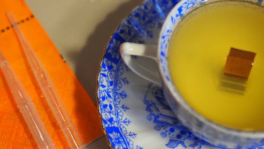 Tasse mit gelber Suppe auf Teller.