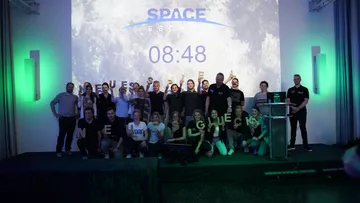 Gruppe von Menschen feiert vor Weltraum-Leinwand.