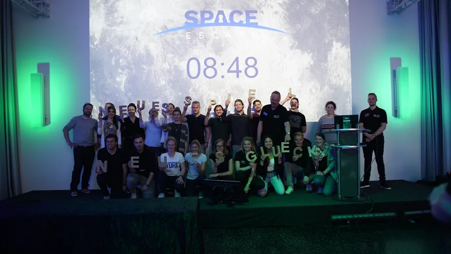 Group of people celebrating in front of space-themed screen.