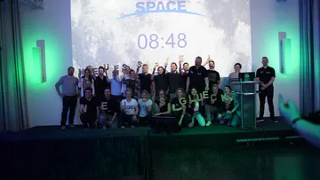 Group posing on stage with space-themed backdrop.